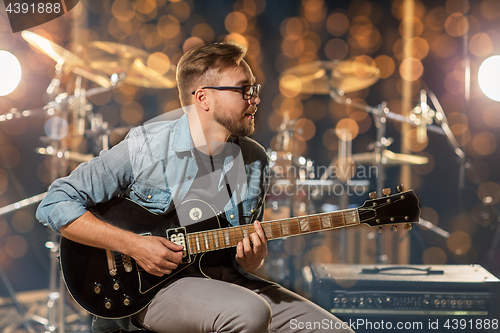 Image of musician playing guitar at studio or music concert