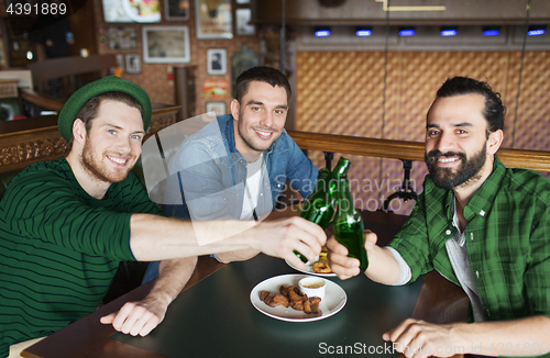 Image of friends drinking beer in bottles at bar or pub