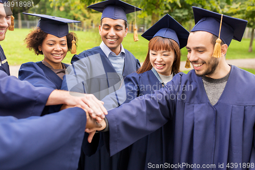 Image of happy students or bachelors in mortar boards