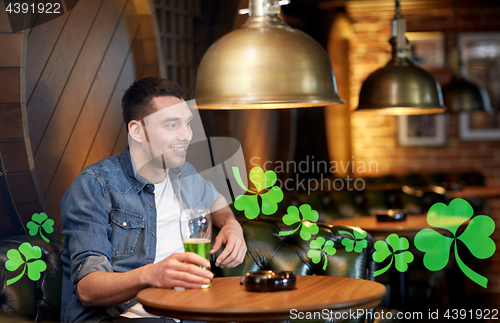 Image of man drinking green beer at bar or pub