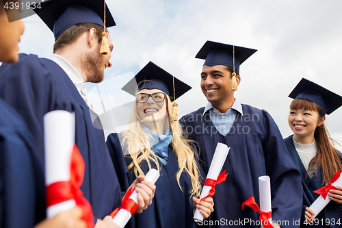 Image of happy students in mortar boards with diplomas