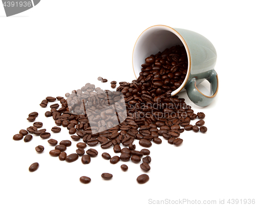 Image of Aromatic roasted coffee beans pour from a green mug