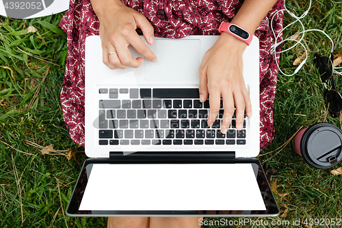 Image of Crop top view of woman using laptop