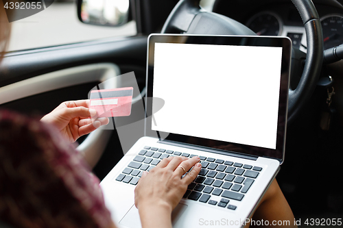 Image of Girl shopping in car using laptop