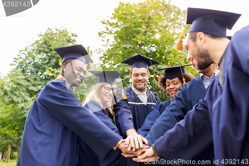 Image of happy students or bachelors in mortar boards