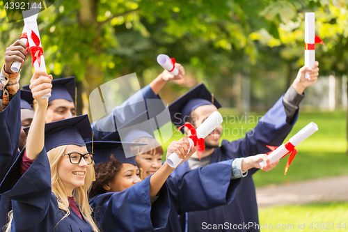 Image of happy students in mortar boards with diplomas