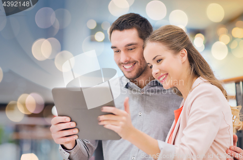 Image of happy couple with tablet pc taking selfie in mall