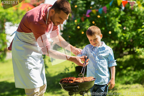 Image of father and son cooking meat on barbecue grill