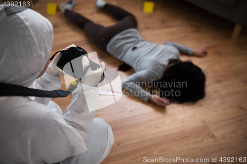 Image of criminalist photographing dead body at crime scene