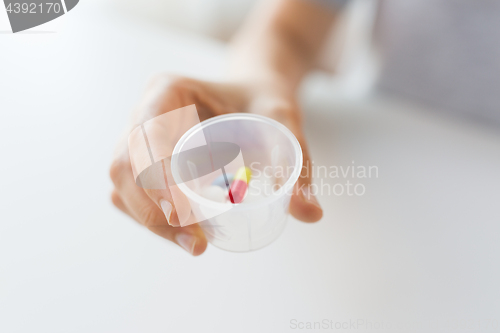 Image of close up of female hand with pills in medicine cup