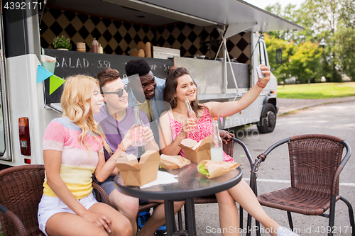 Image of happy young friends taking selfie at food truck