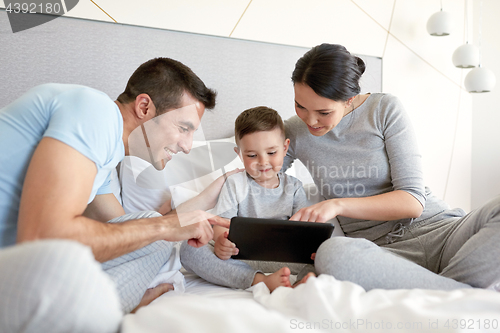 Image of happy family with tablet pc in bed at home