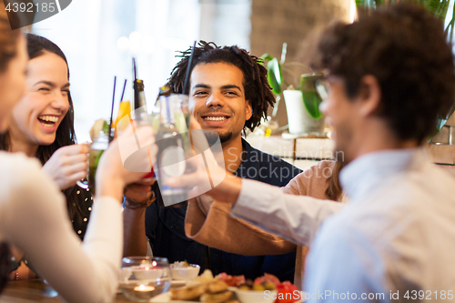 Image of happy friends clinking drinks at bar