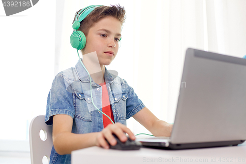 Image of boy in headphones playing video game on laptop