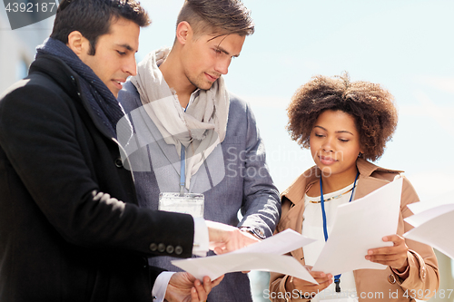 Image of international business team with papers outdoors