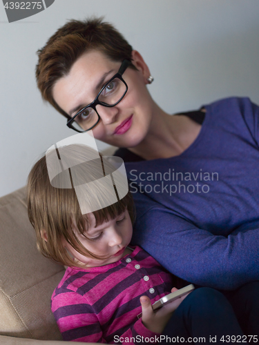 Image of mother and her cute little daughter are using a mobile phone