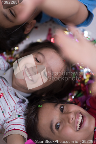 Image of kids  blowing confetti while lying on the floor