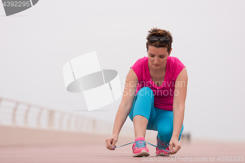 Image of Young woman tying shoelaces on sneakers