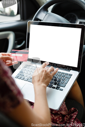 Image of Girl shopping in car using laptop