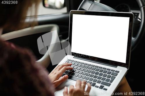 Image of Anonymous woman browsing laptop in car