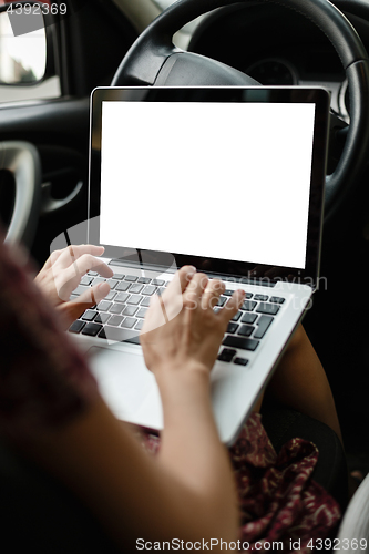 Image of Anonymous woman browsing laptop in car