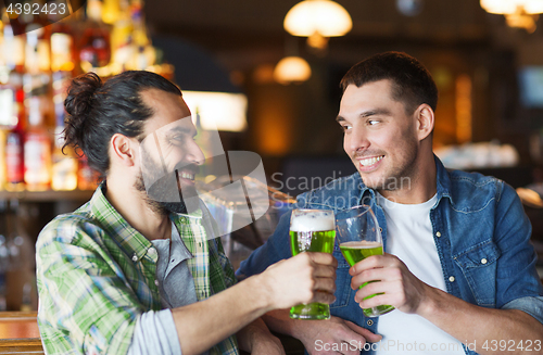 Image of male friends drinking green beer at bar or pub