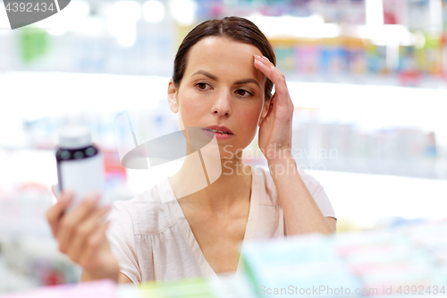 Image of customer with headache choosing drugs at pharmacy