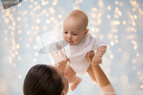 Image of happy mother playing with little baby boy over lights