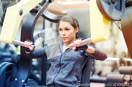 Image of woman flexing muscles on chest press gym machine 