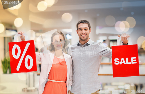 Image of happy young couple with red shopping bags in mall