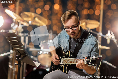 Image of musician playing guitar at studio or music concert