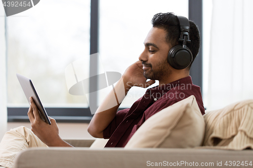 Image of man in phones with tablet pc listening to music