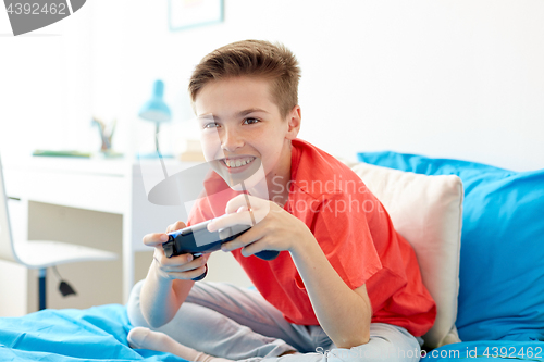 Image of happy boy with gamepad playing video game at home