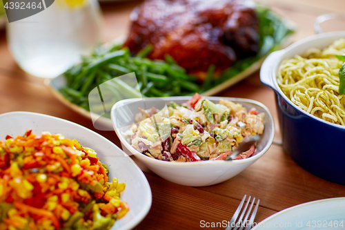 Image of vegetable salad in bowl and other food on table