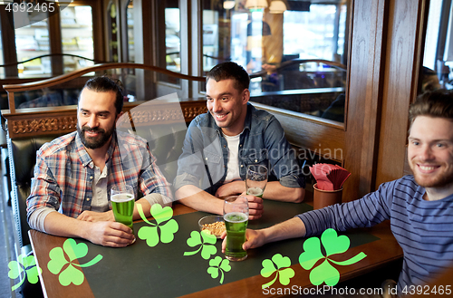 Image of male friends drinking green beer at bar or pub