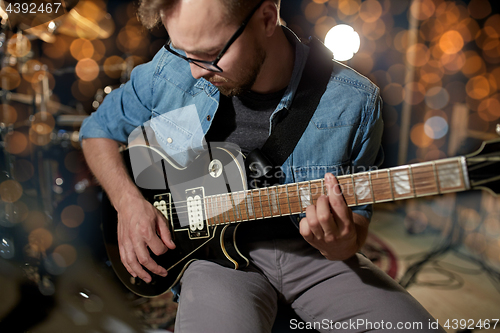 Image of man playing guitar at studio or concert 