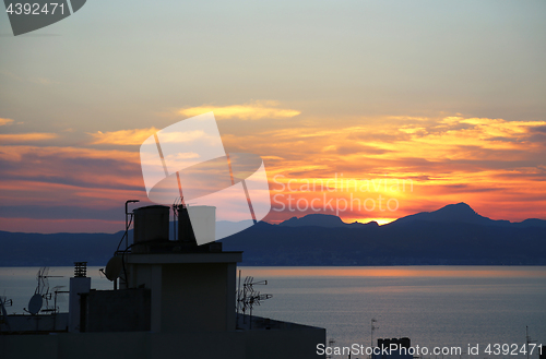 Image of Beautiful sunset on the sea and top of roofs with antennas