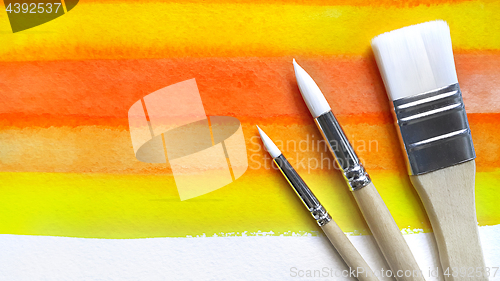 Image of Bright watercolor background and paintbrushes
