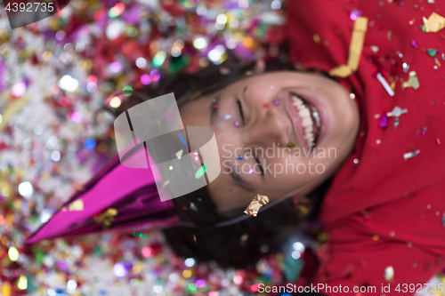 Image of kid blowing confetti while lying on the floor