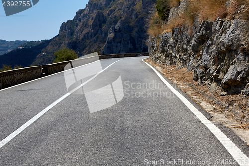 Image of Asphalt road. Colorful landscape with beautiful mountain road with a perfect asphalt. High rocks, blue sky at sunrise in summer. Vintage toning. Travel background. Highway at mountains