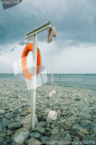 Image of orange lifebuoy on the sea coast