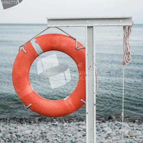 Image of orange lifebuoy on the sea coast