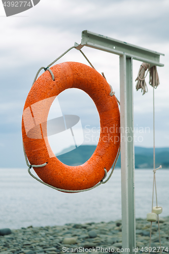 Image of orange lifebuoy on the sea coast