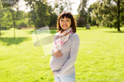 Image of happy pregnant asian woman at park