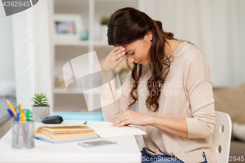 Image of tired female student with book learning at home