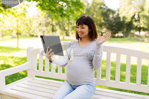 Image of happy pregnant asian woman with tablet pc at park