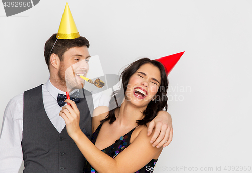 Image of happy couple with party blowers having fun