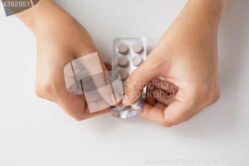 Image of woman hands opening pack of medicine pills