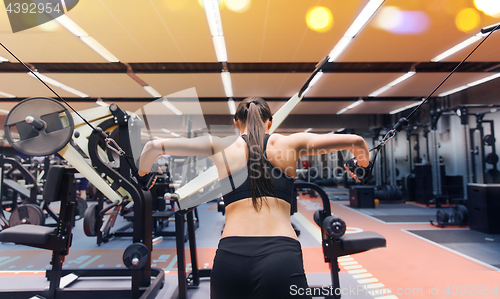 Image of woman flexing muscles on cable machine in gym