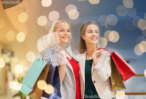 Image of happy young women with shopping bags in mall